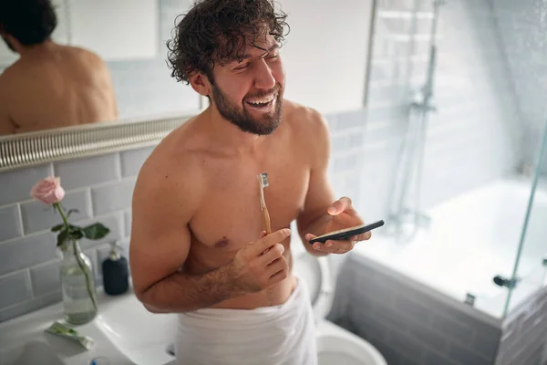 早上在刷牙的时候 快乐的赤裸上身男人在发短信 — 图库照片