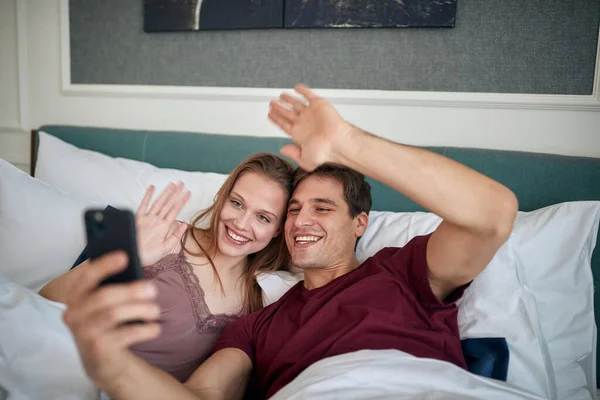 美しい朝にホテルの部屋でベッドの中で自撮りをすることを愛する若いカップル カップル ホテル 一緒に — ストック写真
