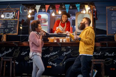Fast food servisindeki çalışanlarla yemek yiyip sosyalleşirken eğlenen, konuşan, gülen, gülen arkadaşlar.