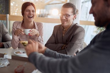 Moladaki genç iş adamları, kahve içiyorlar, gülüyorlar, gülüyorlar, pizza yiyorlar.