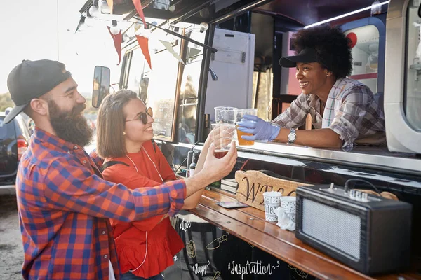 young couple socializing with employee in fast food service having a toast