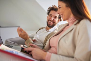 Neşeli iş çifti bir apartmanda rahat bir atmosferde kanepede eğleniyor. İş, çift, eğlence, birlikte.