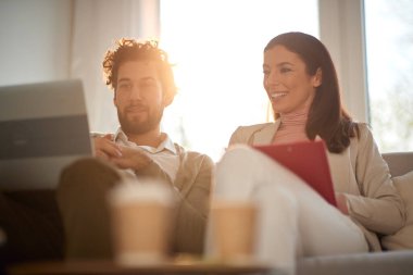 Genç neşeli iş çifti dizüstü bilgisayar içeriğini izliyor ve evden iş yerinde yatakta dinleniyorlar. İş, insanlar, evden çalışmak.