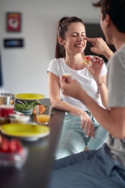 Genç bir çift evde neşeli bir atmosferde kahvaltı ederken eğleniyor. Çift, aşk, kahvaltı, birlikte