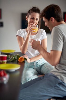 Evde rahat bir atmosferde sabah taze meyve suyu içip sohbet eden genç bir çift. Çift, aşk, kahvaltı, birlikte