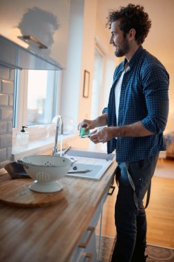 Genç adam mutfakta rahat bir atmosferde ev işi yapmaktan zevk alıyor. Mutfak, ev işleri, Quantin, ev