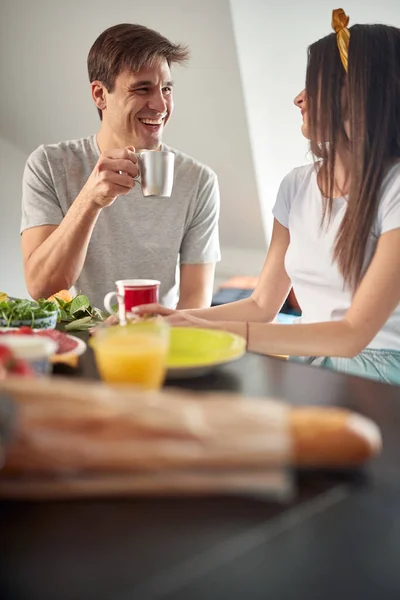 自宅でリラックスした雰囲気の中で朝食前に若いカップルがチャットやコーヒーを楽しんでいます 夫婦関係朝食一緒に — ストック写真