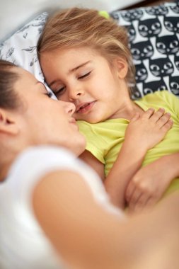 Anne ve kızı yatakta birlikte uyuyorlar.