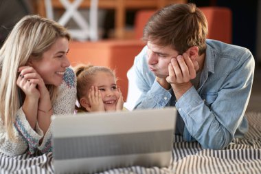 Ebeveynler kızlarıyla birlikte bilgisayarda oynuyorlar.