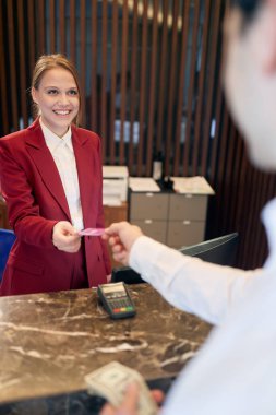 Tezgahın arkasında misafirleri kabul eden hoş bir bayan resepsiyonist. Turizm, iş, otel