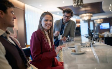 Genç bir iş kadını iş arkadaşlarıyla barda rahat bir ortamda kahve molası veriyor. İş, insanlar, bar.