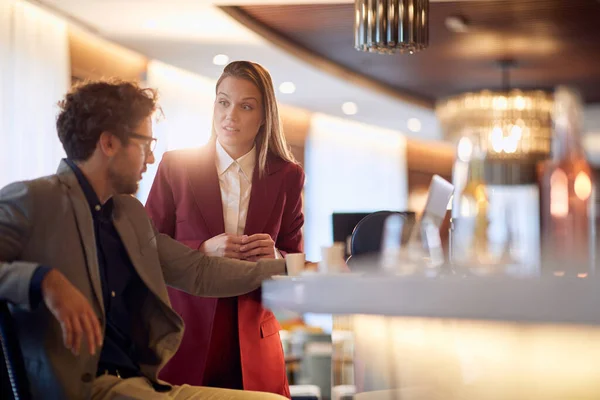 Young businesswoman talking to a young male colleague at coffee break in a relaxed atmosphere at the bar. Business, people, bar