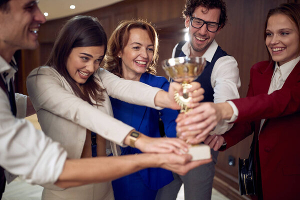 Коллеги в атмосфере победителя отмечают командный успех и награду на бизнес-конференции в отеле. Гостиница, бизнес, люди