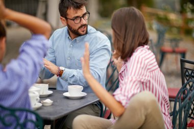 Bir grup arkadaş, güneşli bir günde barın avlusunda kahve içerken tartışıyorlar. Arkadaşlık, birlikte, dışarıda, barda.