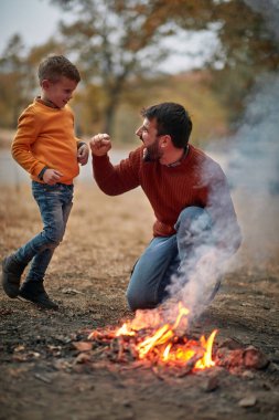 Baba ve küçük oğlu doğada kamp ateşi hazırlıyorlar. 