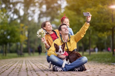 Parkta selfie çeken üç kişilik mutlu bir aile.