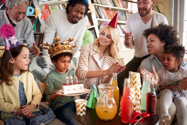 Family and friends singing a birthday song to a little celebrant at his birthday party in a festive atmosphere at home. Family, celebration, together