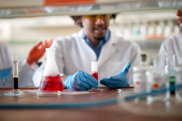 Young colleagues in a protective gear discuss about an experiment they doing in a relaxed atmosphere in the university laboratory. Science, chemistry, lab, people