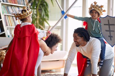 Şövalye gibi giyinmiş çocuklar, ailelerine biniyorlar ve evlerinde şövalye oyunu oynuyorlar. Aile, ev, oyun zamanı