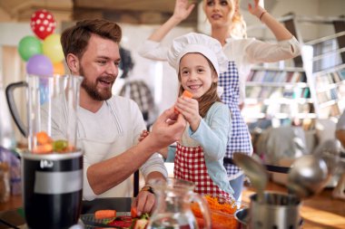 Küçük bir kız ve babası evde neşeli bir atmosferde yemek hazırlarken fotoğraf için poz veriyorlar. Aile, ev, mutfak.