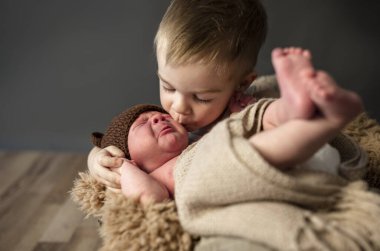 Küçük çocuk kardeşini öpüyor.