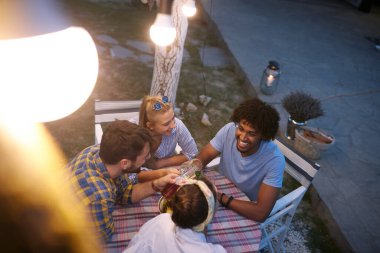 Bir araya gelen, sosyalleşen, konuşan, gülümseyen, masada oturan çok ırklı arkadaş grubunun üst görüşü.