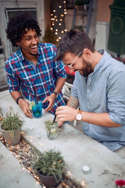 Male friends having a good time at the bar\'s backyard on a beautiful weather. Quality friendship time together