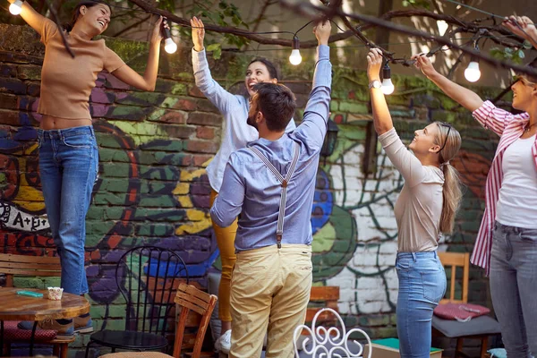 在一个美丽的日子里 一群快乐的朋友正在酒吧的花园里享受着狂欢派对的准备工作 — 图库照片