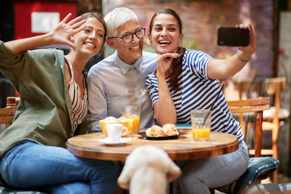 A group of female friends of different generations taking a selfie while they have a drink in a cheerful atmosphere in the bar together after long time. Leisure, bar, friendship, outdoor