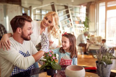 The happy family is satisfied with how they planted flowers in a cheerful atmosphere at home. Family, leisure, together