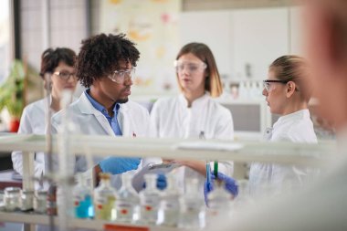Young students discussing about the experiment in a sterile environment of the laboratory. Science, chemicals, lab, people