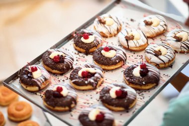 Bir tepsi dolusu el yapımı lezzetli donutlar bir pastane için hazır. Hamur işi, tatlı, tatlı,