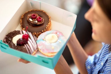 Bir pastanenin hoş atmosferinde güzel bir kız lezzetli çöreklerle dolu bir kutu tutuyor. Pastane, tatlı, tatlı