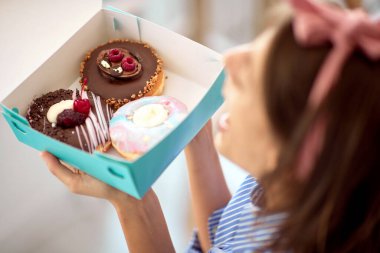 Bir pastanede hoş bir atmosferde güzel bir kız lezzetli çöreklerle dolu bir kutu yüzünden çok mutlu. Pastane, tatlı, tatlı