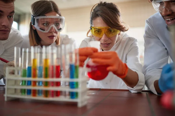 Young chemistry students in a cheerful atmosphere in a laboratory are watching a chemical reaction in an experiment. Science, chemistry, lab, people