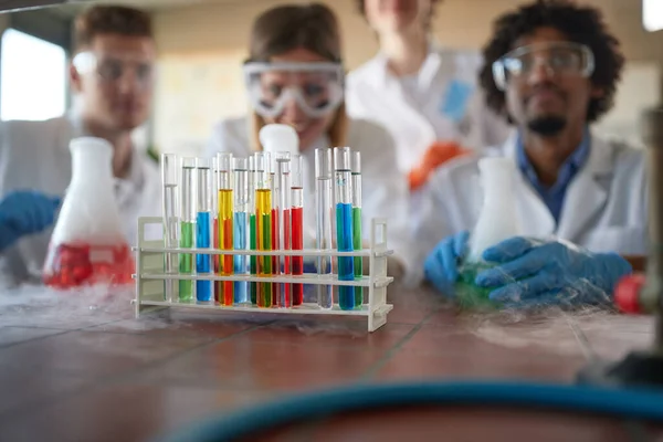 Young chemistry students in a sterile laboratory environment are enjoying observing colorful chemical reactions. Science, chemistry, lab, people