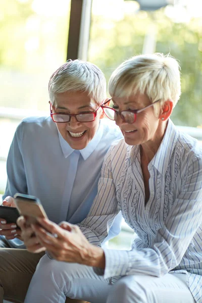 Duas Mulheres Negócios Idosas Aparência Semelhante Desfrutam Conteúdo Smartphone Pausa — Fotografia de Stock