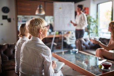 Bir grup bayan ofis çalışanı, iş yerindeki hoş bir atmosferde bayan meslektaşlarının sunumunu izlemekten zevk alıyor. İş, ofis, iş