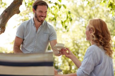 Sakallı koca, karısına kocaman gülümseyerek bir fincan kahve veriyor.
