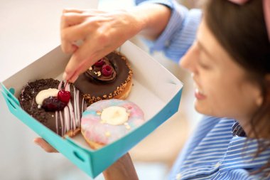 Neşeli kadın evde lezzetli çörekler yiyor.