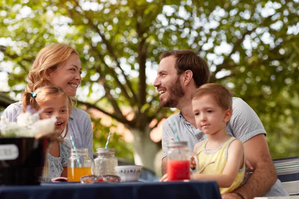 Happy Caucasian Parents Looking Each Other Smiling Children Laps Sitting — Foto de Stock