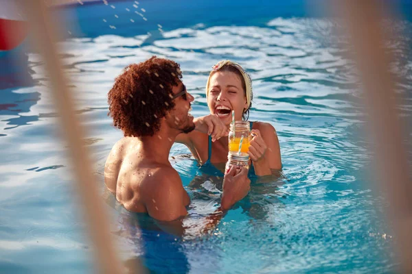 屋外プールでジュースを手に笑っている若い多民族のカップルは — ストック写真