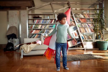 Sırtında roket oyuncağı olan küçük bir çocuk uzaya uçtuğunu hayal ederken rahat bir atmosferde eğleniyor. Ev, oyun, çocukluk