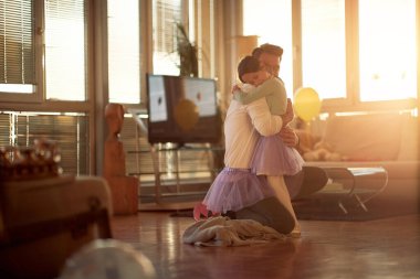 Genç bir baba ve küçük kızı evde güzel bir atmosferde bale eğitimi alırken kucaklaşıyorlar. Aile, birlikte, ev