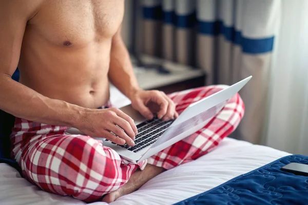 魅力的な白人男性の半分裸の白人男性がベッドに座ってノートパソコンに入力し — ストック写真