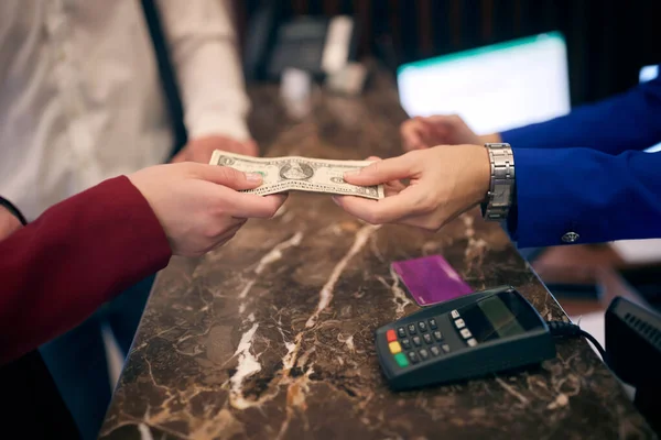 paying in cash at hotel reception. detail, hands, from hand to hand