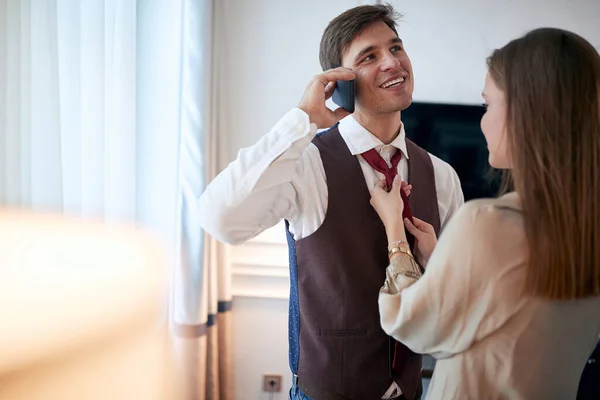 若い白人女性が彼の携帯電話で話している若い男性とのネクタイを固定笑顔 — ストック写真