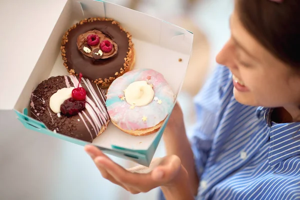 제과점의 분위기 속에서 아름다운 가손에 맛있는 도넛이 상자를 열정적으로 바라보고 — 스톡 사진