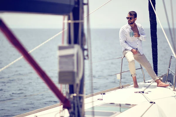 若いハンサムな男性モデルは 海辺の美しい晴れた日にヨットでの写真撮影で太陽とコーヒーを楽しんでいます — ストック写真