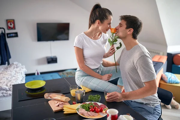 恋のカップルは一緒に家でロマンチックな雰囲気の中でバレンタインデーの朝食を持っている間にバラの香りがしています 一緒に — ストック写真